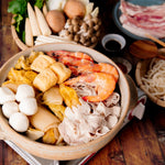 Traditional Pickled Cabbage Pork Hot Pot Soup filled with shrimp, sliced pork, mushrooms, tofu and veggies ready to be cooked at the table with noodles and dipping sauce on the side.